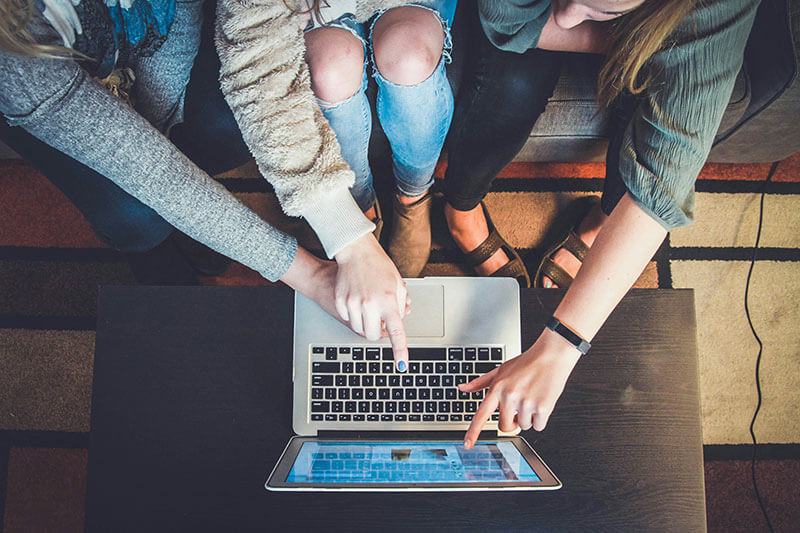 Three students searching for colleges on a computer